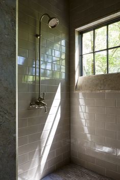 a bathroom with a shower head, window and tiled walls in the corner next to it