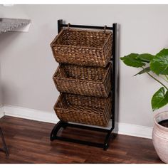 three wicker baskets sitting on top of a metal stand next to a potted plant