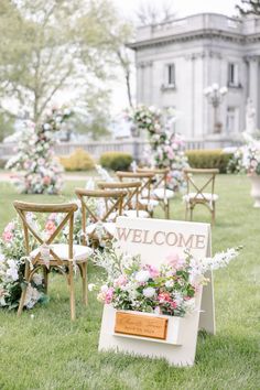 an outdoor ceremony with wooden chairs and flowers on the grass, in front of a large building