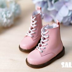 a pair of pink baby boots sitting on top of a wooden table next to flowers