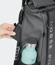 a person is holding a water bottle in their back pack