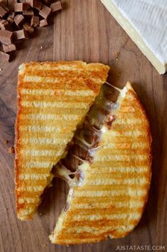 a grilled cheese sandwich cut in half on top of a wooden cutting board with chocolate chunks