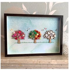 two trees with buttons in the shape of flowers on a shelf next to a wall