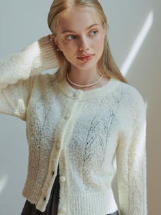 a woman wearing a white sweater and black skirt