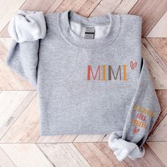 Custom Mimi Embroidered Sweatshirt With Kids Names All hoodies and crewneck sweatshirts are fleece. 65% cotton 35% poly Care instructions: Machine cold wash, inside out, with like colors. Only non-chlorine bleach. Tumble dry low. Medium iron. Do not iron decoration. Double-needle stitched neckline, bottom hem and sleeves t-shirt. Unisex sizing. Size chart is available in the listing photos. All measurements are approximate. Measurements may vary about 2″ less or more. Fall Fleece Sweater With Embroidered Logo, Fleece Sweater With Letter Embroidery For Fall, Gray Letter Embroidery Sweatshirt For Fall, Fall French Terry Sweatshirt With Embroidered Logo, Gray Embroidered Logo Sweatshirt For Fall, Fleece Sweatshirt With Letter Embroidery For Fall, Personalized Cotton Sweatshirt For Mother's Day, Mother's Day Sweatshirt With Name Print And Crew Neck, Personalized Long Sleeve Sweatshirt For Mother's Day