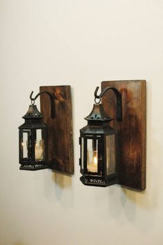 two wooden wall sconces mounted to the side of a white wall with candles in them