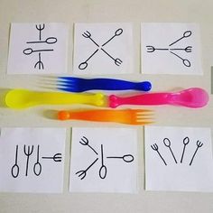 four different colored plastic forks and spoons on top of white paper with black writing