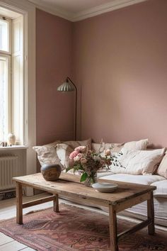 a living room with pink walls and white furniture