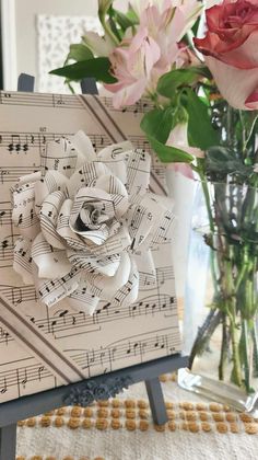 a vase filled with pink flowers next to sheet music