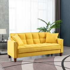 a yellow couch sitting on top of a rug in a living room next to a window