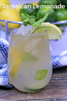 a glass filled with lemonade sitting on top of a table next to limes