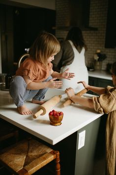 two children are playing with dough on the kitchen counter