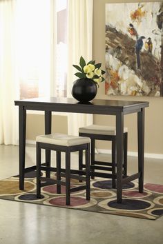 a dining room table with two stools and a vase on top of the table