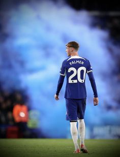 a man standing on top of a soccer field wearing a blue and white uniform with the number 20 on it