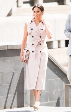 a woman in a trench coat is walking down the street