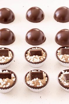 chocolates and marshmallows are arranged in rows on a white surface,