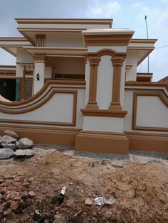 a white and brown house with some rocks on the ground