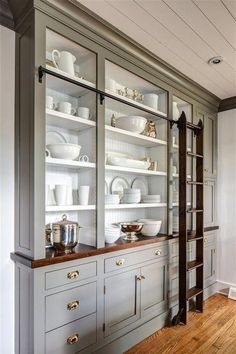 a large china cabinet with glass doors and shelves filled with dishes on top of it