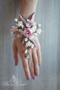 a woman's hand holding a pink and white wrist corsage with flowers on it