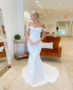 a woman in a white dress is posing for the camera with her hands on her hips