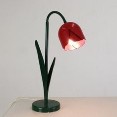 a desk lamp with a red shade on it's head sitting on a white surface