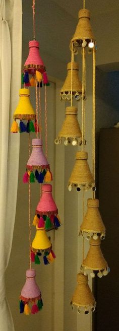 a bunch of colorful bells hanging from a ceiling in a room with curtains and windows