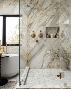 a bathroom with marble walls and flooring next to a bathtub in the corner