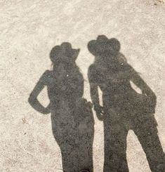 two people standing next to each other with their shadows cast on the ground behind them