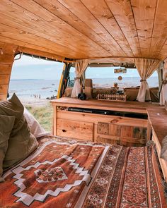 the inside of a van with a bed and rugs on the floor next to it