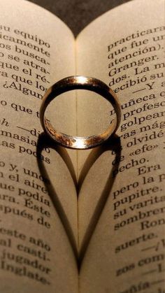 a heart shaped ring casts a shadow on an open book