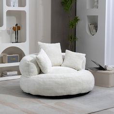 a living room with a white chair and some books on the shelf above it,