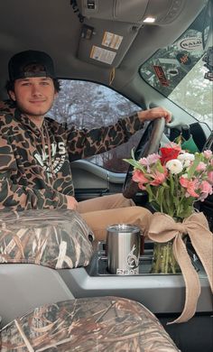 a man sitting in the back seat of a car with flowers on the dash board