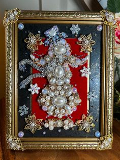 a christmas tree made out of pearls and other jewels in a frame on a table