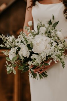 a bride holding a bouquet of white flowers