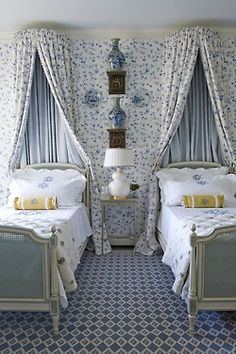 two beds in a room with blue and white wallpaper