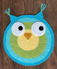 a crocheted owl rug on a wooden floor with eyes and ears, made to look like an owl