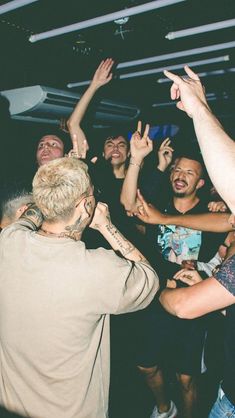 a group of people standing around each other with their hands in the air