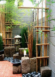 an outdoor garden with rocks and plants in the center, surrounded by bamboo poles and other greenery