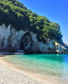 there is a boat that is sitting in the water at the beach by the cliff