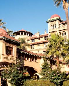 an old building with palm trees in the foreground and a clock tower on top