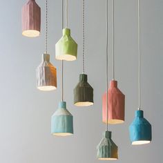 a bunch of different colored lights hanging from the ceiling in a room with gray walls