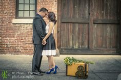 a man and woman standing next to each other in front of a building with a suitcase