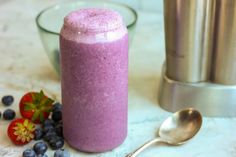 a smoothie with blueberries and strawberries next to a shaker on a table