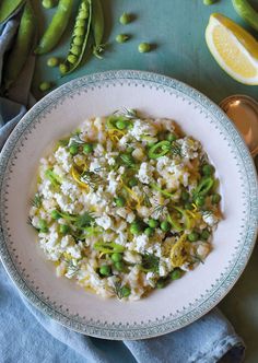 a white plate topped with rice and vegetables next to lemon wedges on a blue table cloth