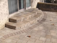 a brick patio with steps leading up to the front door and side windows on both sides