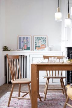 two wooden chairs sitting at a table in front of a fireplace