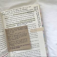 an open book with a piece of paper pinned to it's side next to a pile of other books