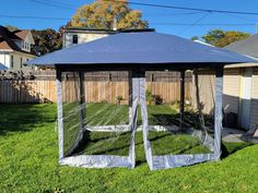 a blue gazebo sitting in the grass next to a fence and yard with houses behind it