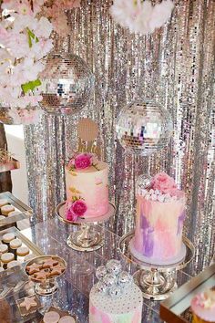 a table topped with lots of cakes and cupcakes next to a disco ball