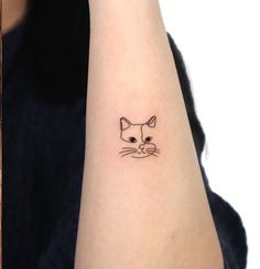 a small cat tattoo on the left wrist and right arm, which is drawn in black ink